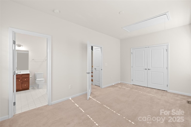 unfurnished bedroom with ensuite bath, light colored carpet, and a closet