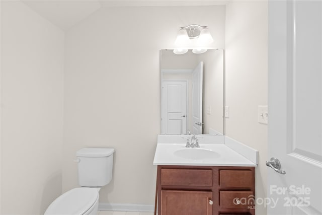 bathroom with toilet, vanity, and vaulted ceiling