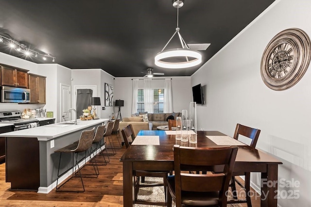 dining area with dark wood-type flooring, ceiling fan, and sink