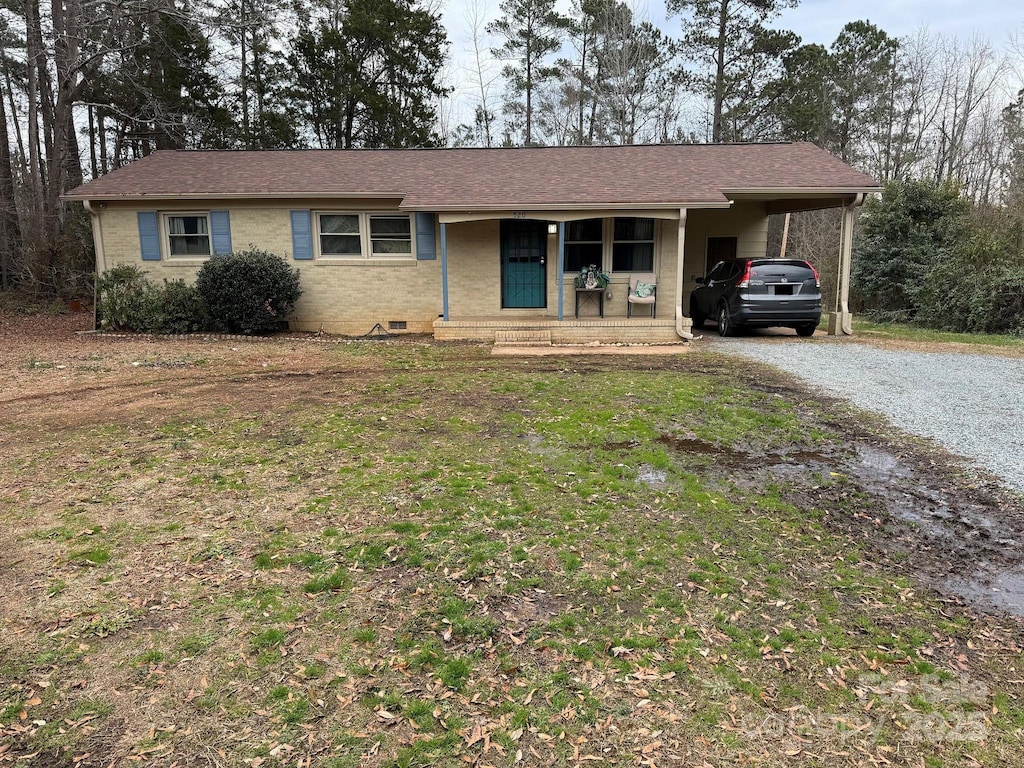 ranch-style home featuring a front lawn, covered porch, and a carport