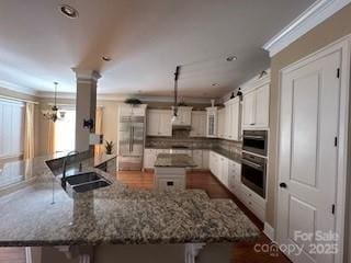 kitchen with white cabinetry, sink, stainless steel appliances, decorative light fixtures, and a kitchen bar