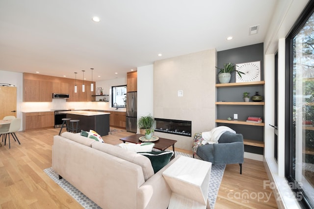 living room featuring sink, a tiled fireplace, and light hardwood / wood-style flooring