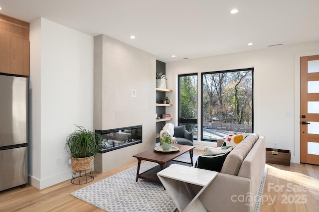 living room with light hardwood / wood-style floors, a tile fireplace, and plenty of natural light