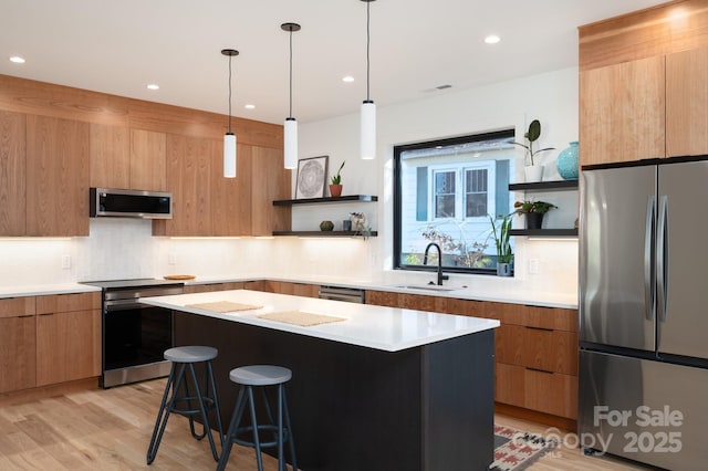 kitchen with stainless steel appliances, sink, a kitchen bar, light hardwood / wood-style flooring, and a kitchen island