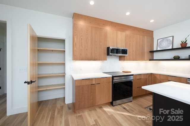 kitchen with backsplash, light hardwood / wood-style floors, and appliances with stainless steel finishes