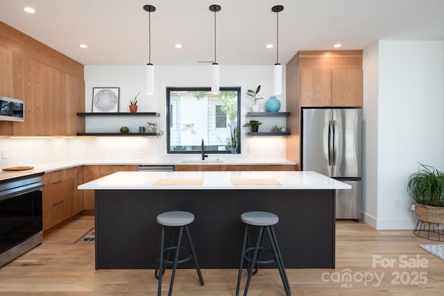 kitchen featuring appliances with stainless steel finishes, a breakfast bar, a center island, and sink