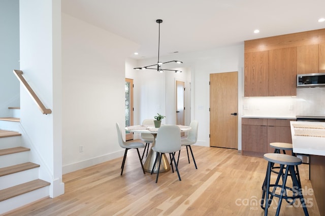 dining space featuring light wood-type flooring and an inviting chandelier