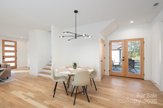 dining room with light hardwood / wood-style flooring, french doors, and an inviting chandelier