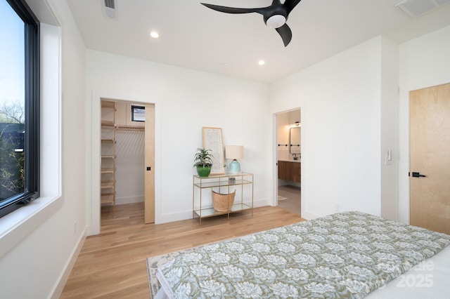 bedroom featuring a walk in closet, multiple windows, a closet, and ceiling fan