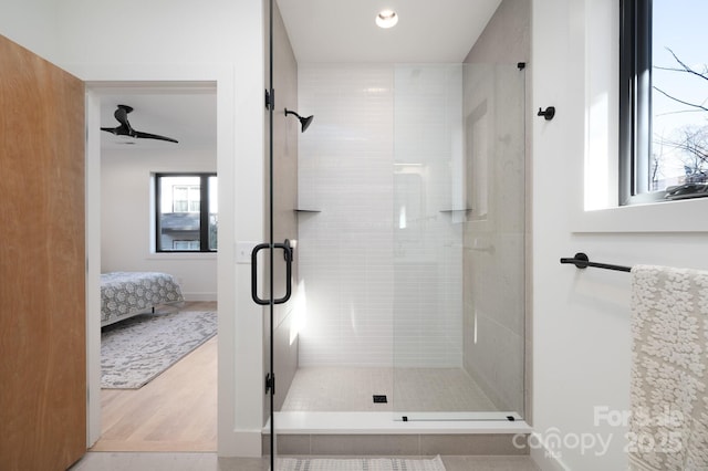 bathroom with ceiling fan, a shower with shower door, and hardwood / wood-style floors