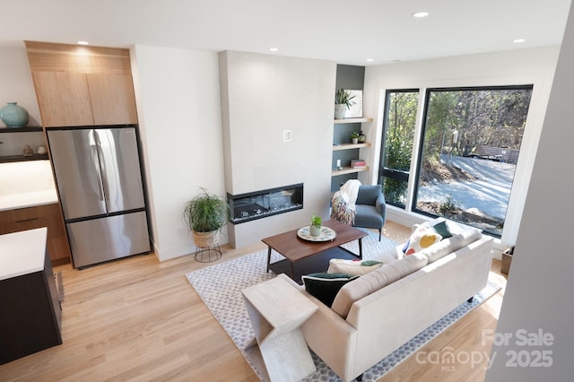 living room featuring light wood-type flooring, a wealth of natural light, and a large fireplace