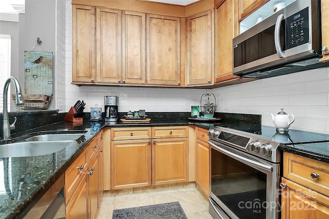 kitchen featuring stainless steel appliances, light tile patterned floors, dark stone counters, decorative backsplash, and sink