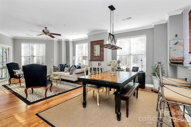 dining space featuring a wealth of natural light, ceiling fan, crown molding, and wood-type flooring