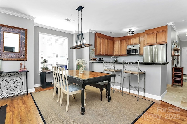 dining space with ornamental molding and wood-type flooring