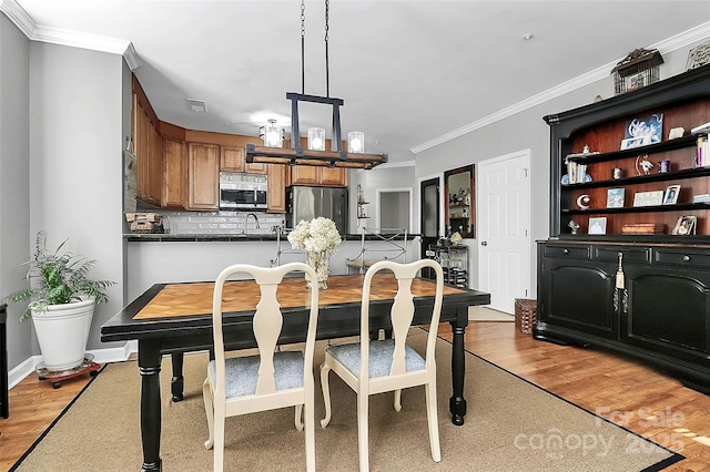 dining space featuring light wood-type flooring and crown molding