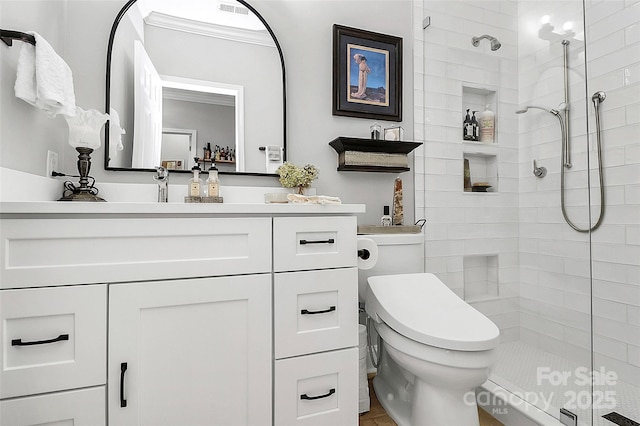 bathroom with toilet, a tile shower, vanity, and crown molding