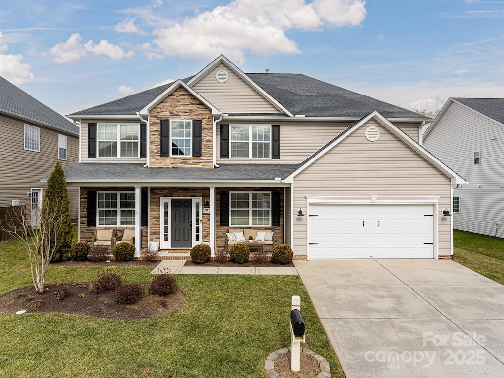 view of front of home featuring a garage, a front yard, and covered porch