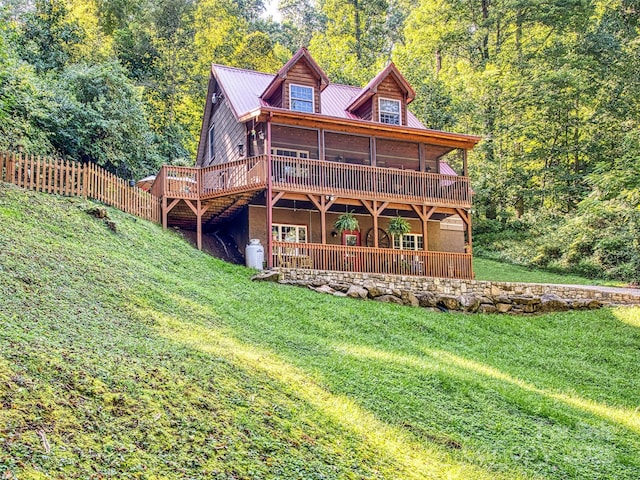 rear view of house featuring a sunroom, a yard, and a deck