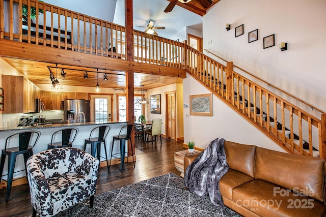 living room with dark hardwood / wood-style flooring, a towering ceiling, and ceiling fan