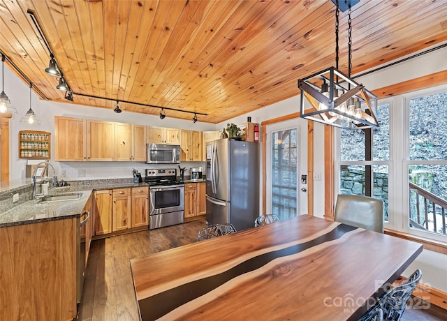 kitchen with sink, decorative light fixtures, dark stone countertops, appliances with stainless steel finishes, and dark hardwood / wood-style floors