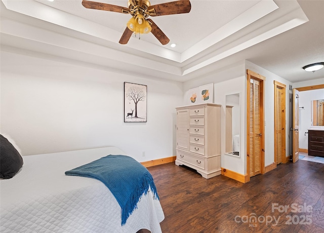 bedroom with ceiling fan, dark hardwood / wood-style flooring, and a raised ceiling