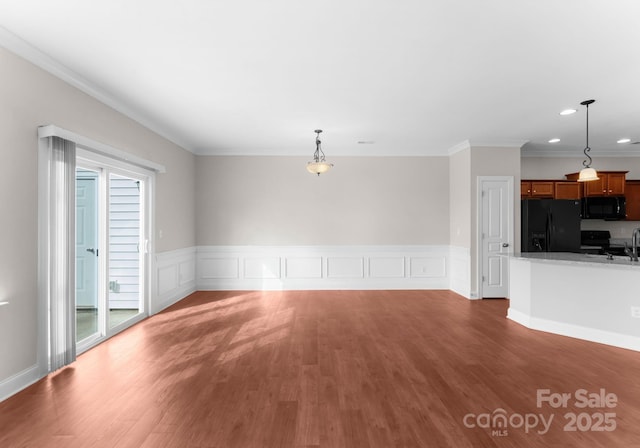 unfurnished living room featuring dark wood-type flooring, plenty of natural light, and crown molding