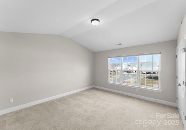 carpeted spare room with vaulted ceiling