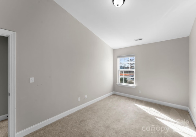 carpeted spare room featuring vaulted ceiling