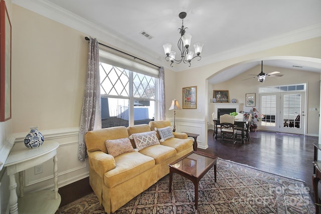 living room featuring vaulted ceiling, dark wood-type flooring, ceiling fan with notable chandelier, and ornamental molding