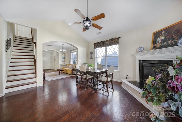 dining room featuring a high end fireplace, vaulted ceiling, dark wood-type flooring, and ceiling fan with notable chandelier