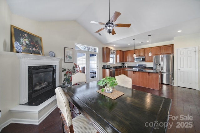 dining space featuring ceiling fan, dark hardwood / wood-style floors, a high end fireplace, and vaulted ceiling