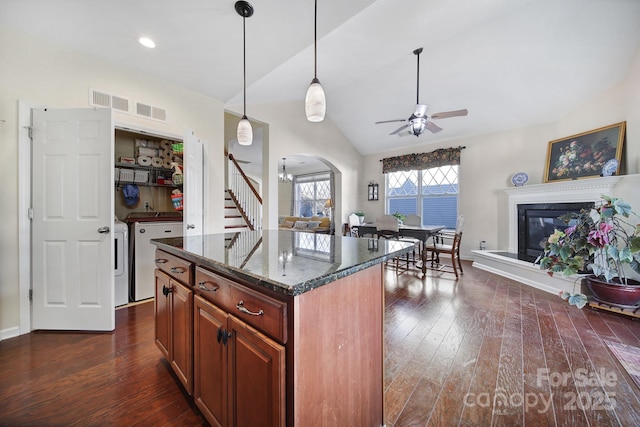 kitchen featuring pendant lighting, lofted ceiling, a kitchen island, dark hardwood / wood-style floors, and independent washer and dryer