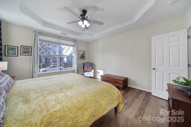 bedroom featuring ceiling fan, wood-type flooring, and a raised ceiling