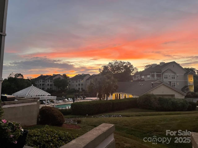 yard at dusk featuring a fenced in pool