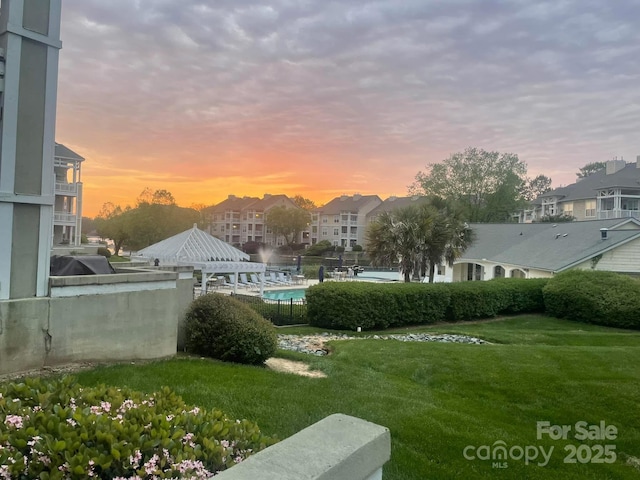 yard at dusk featuring a gazebo and a community pool