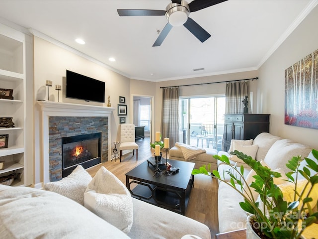 living area with built in shelves, recessed lighting, a fireplace, light wood-type flooring, and crown molding