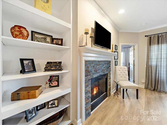 interior space with a fireplace, wood finished floors, baseboards, built in features, and crown molding