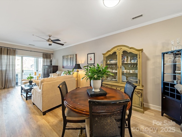 dining room featuring visible vents, baseboards, ceiling fan, ornamental molding, and light wood-style floors