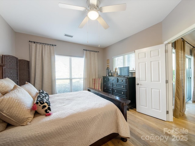 bedroom with light wood-style floors, multiple windows, visible vents, and a ceiling fan