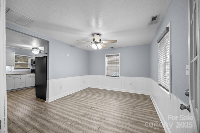 empty room with light wood-type flooring and a textured ceiling