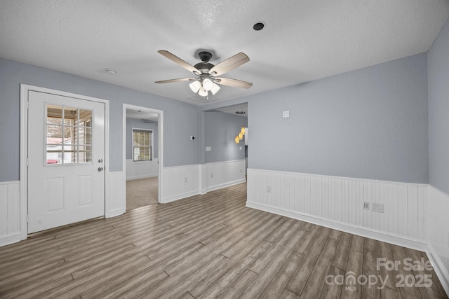 unfurnished room with ceiling fan, a textured ceiling, and light wood-type flooring