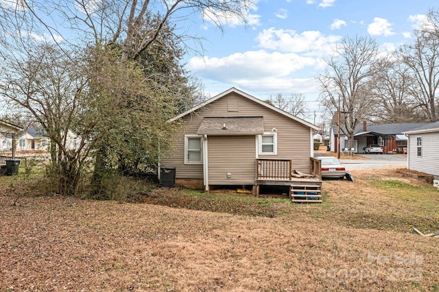 rear view of house with central air condition unit and a lawn