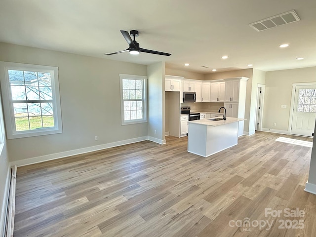 kitchen with appliances with stainless steel finishes, sink, a center island with sink, white cabinets, and light hardwood / wood-style floors