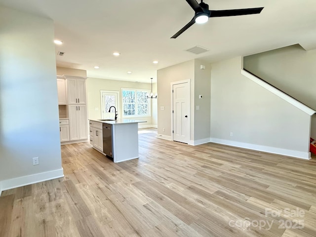 kitchen with white cabinetry, a center island with sink, stainless steel dishwasher, and light hardwood / wood-style flooring