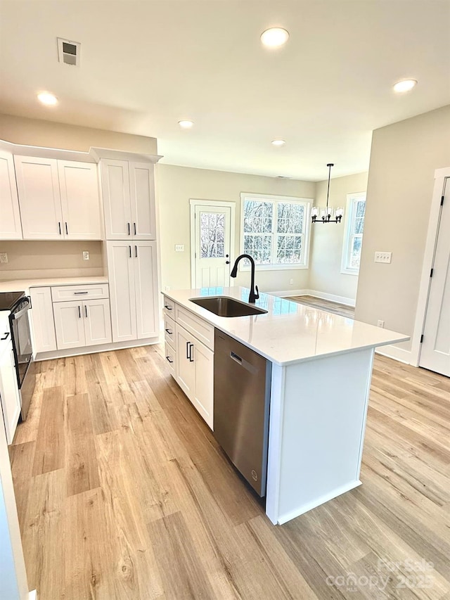 kitchen with appliances with stainless steel finishes, sink, a center island with sink, white cabinetry, and hanging light fixtures