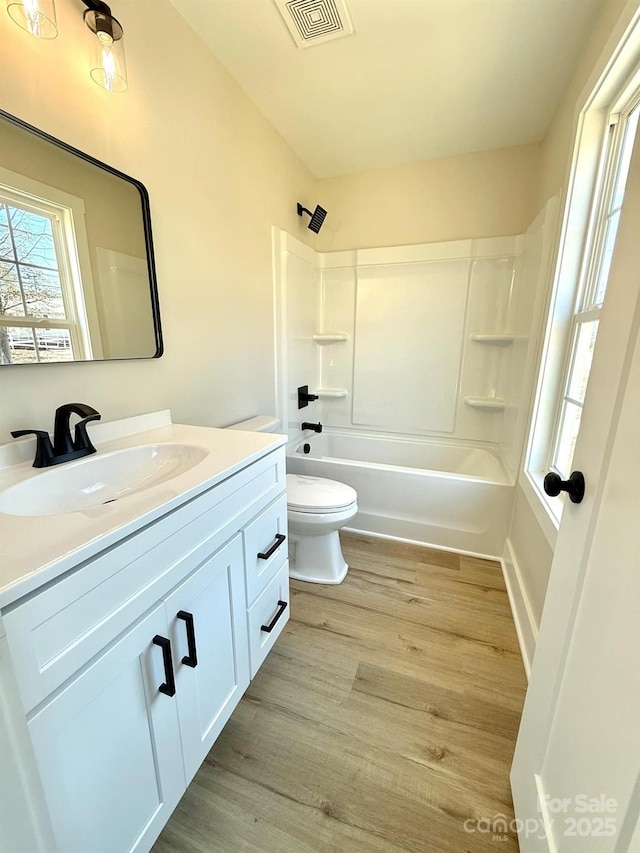 full bathroom with hardwood / wood-style floors, vanity,  shower combination, and toilet