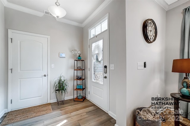 entrance foyer featuring ornamental molding and light hardwood / wood-style flooring