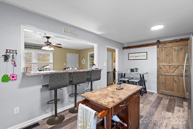 dining area with ceiling fan, hardwood / wood-style floors, and a barn door