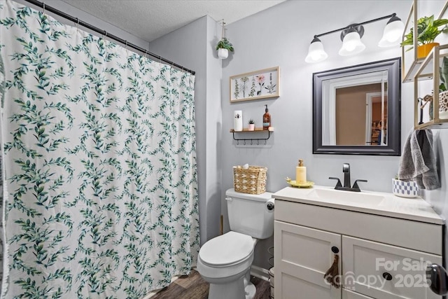 bathroom with a textured ceiling, hardwood / wood-style flooring, a shower with curtain, toilet, and vanity