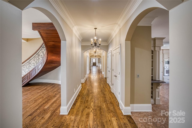 hall with ornamental molding, dark hardwood / wood-style flooring, and an inviting chandelier